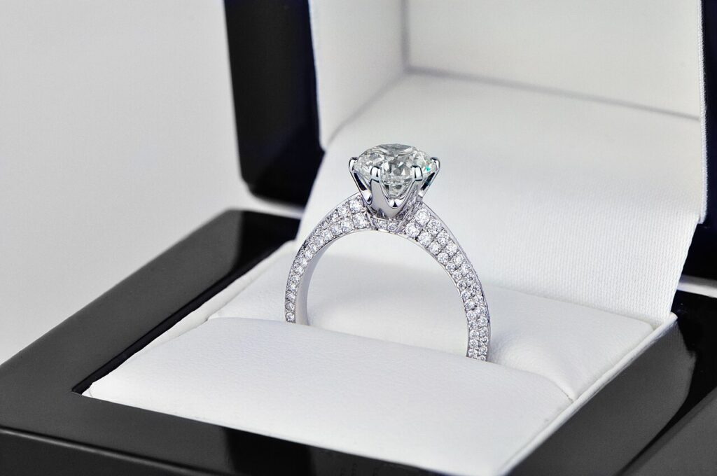Pierścionek zaręczynowy solitaire z okrągłym diamentem w oprawie łapkowej i szyną wysadzaną drobnymi diamentami pavé